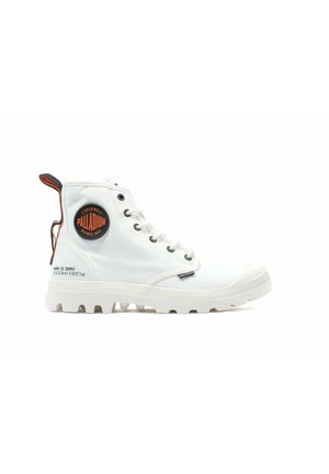 Bottes montantes blanches en toile avec une semelle en caoutchouc, dotées d'un patch logo rond, de lacets gris et d'une languette à l'arrière en orange.