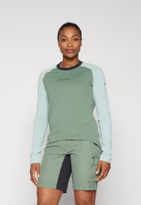 Langermet skjorte i olivengrønn med lys blå detaljer, med rund halslinning og logo, satt sammen med matchende olivengrønne shorts med lommer.