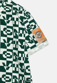 Zielona i biała koszula krótki rękaw w kratkę z napisem "VINGINO" oraz pomarańczową metką z detalami logo.