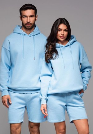 Lyseblå matchende sweatshirts og shorts lavet af blødt stof. Sweatshirts har snoretræk; shortsene har en sidelomme og op-rullede kanter.