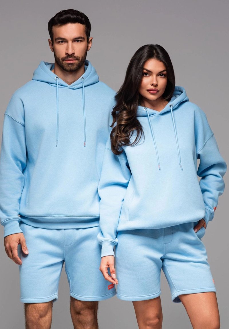 Ljusblå matchande hoodies och shorts i mjukt tyg. Hoodies har dragsko; shorts har sidficka och upprullade fållar.
