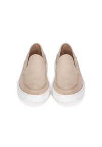 Zapatillas de ante beige sin cordones con punta redondeada y suela de goma blanca, que presentan un acabado de costuras bien hechas a lo largo de los bordes.