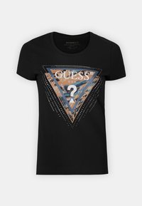 Svart t-shirt med rund hals, prydd med en triangelformad GUESS-grafik i brunt och blått med metalliska detaljer och vita prickmönster.