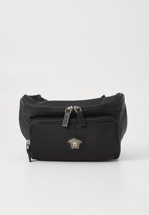 Schwarze Nylon-Tasche mit zwei Reißverschlusstaschen, ausgestattet mit einem silbernen Medusa-Emblem und gebrandeten Reißverschlüssen. Glatte Textur, kompaktes Design.