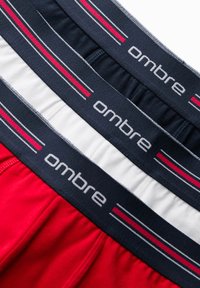 Tre par herrboxershorts i röd, vit och marinblå. Varje par har en marinblå midjeresår med "ombre" och röd/vit rand. Materialet är bomull.