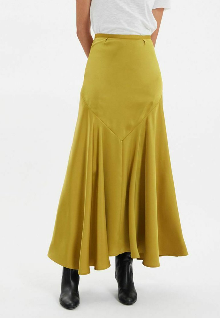 Jupe longue et fluide d'un jaune moutarde vibrant, confectionnée en tissu lisse. Dotée d'une taille haute et d'un design plissé pour plus de mouvement.