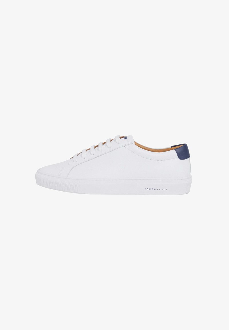Sneakers bianchi in pelle con una texture liscia, dotati di un accento in blu navy sul tallone, lacci rotondi e una suola in gomma con un branding minimale.