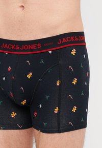Sötétkék boxer alsónadrág ünnepi mintákkal, beleértve a mézeskalács embereket, cukorpálcákat és fagyöngyöt. Piros derékpánton "JACK & JONES MERRY" felirattal.