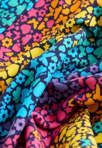 Bunt gemustertes Textil mit schwarzem Hintergrund und lebhaften Blumen-, Herz- und Sternmustern in Blau, Pink, Orange und Gelb. Strukturierter Stoff.