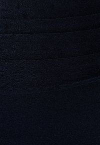 Tamsiai mėlyna tampri medžiaga su lygiu paviršiumi, pasižyminti horizontaliomis ribuotos tekstūros linijomis, suteikiančiomis papildomo detališkumo ir elastingumo. Tinka prigludusiam drabužiams.