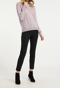 Jasnofioletowy sweter z długimi rękawami, prążkowanymi mankietami i w pasie; zestawiony z czarnymi spodnimi slim-fit i czarnymi botkami za kostkę.