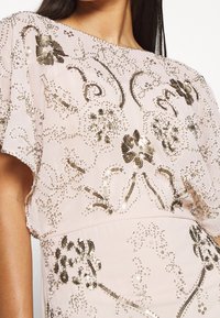 Pärlad rosa klänning med blommönster, lätt tyg och korta ärmar med intrikata detaljer och skimrande paljetter.