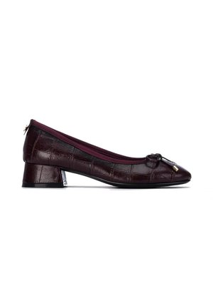 Zapato de tacón bajo de color burdeos oscuro con textura de cocodrilo, punta redondeada, ribete de tela y pequeño lazo con puntas metálicas en la parte superior.