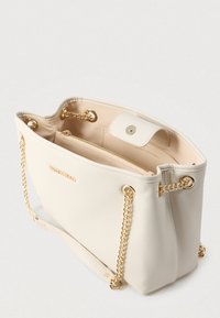 Hvit lærveske med gullfargede kjedestropper, glidelåslomme og sikker trykknappåpning. Har teksturert overflate og mykt interiør.