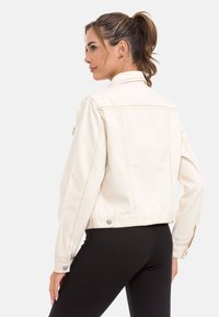Witte denim jacket met een klassieke kraag, zichtbare stiksels en knoopaccenten. Doorzichtig textuur, cropped ontwerp dat de taille bereikt.