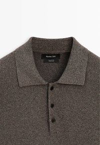 Braunes, geripptes Baumwoll-Poloshirt mit drei schwarzen Knöpfen und klassischem Kragen.