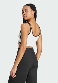 Witte en zwarte crop top met een ronde hals, met contrasterende zwarte afwerking. Gecombineerd met zwarte rib gebreide wijde broek.