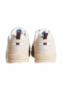 Sneakers beige con design in suede e mesh, dotati di colletto imbottito e accenti marroni a contrasto. Include branding in rilievo sul tallone.