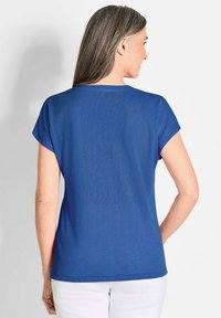 Blauwe T-shirt met korte mouwen van katoen. Eenvoudig ontwerp met een ronde hals en een rechte zoom. Lichtgewicht stof met een gladde textuur.