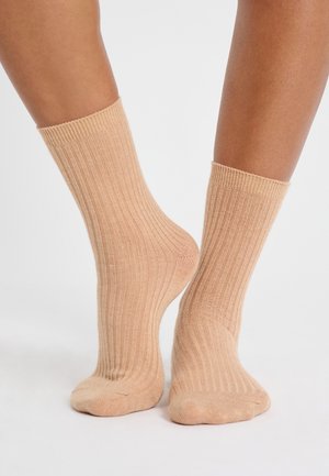 Lichtbeige geribde sokken met een zachte textuur, van middenkalfs lengte, en afgewerkt met een snug fit manchet aan de bovenkant.
