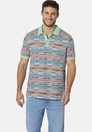 Lächelnder Mann trägt ein kurzärmeliges Poloshirt mit mehrfarbigen horizontalen Streifen und mintgrünem Kragen und Ärmelbündchen, kombiniert mit hellblauen Jeans.