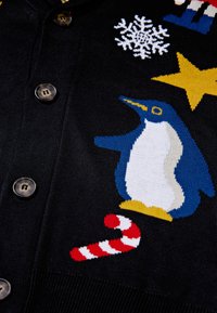 Cardigan nero a maglia con bottoni, caratterizzato da design a maglia colorati di un pinguino, una canna di zucchero, un fiocco di neve bianco e una stella gialla.