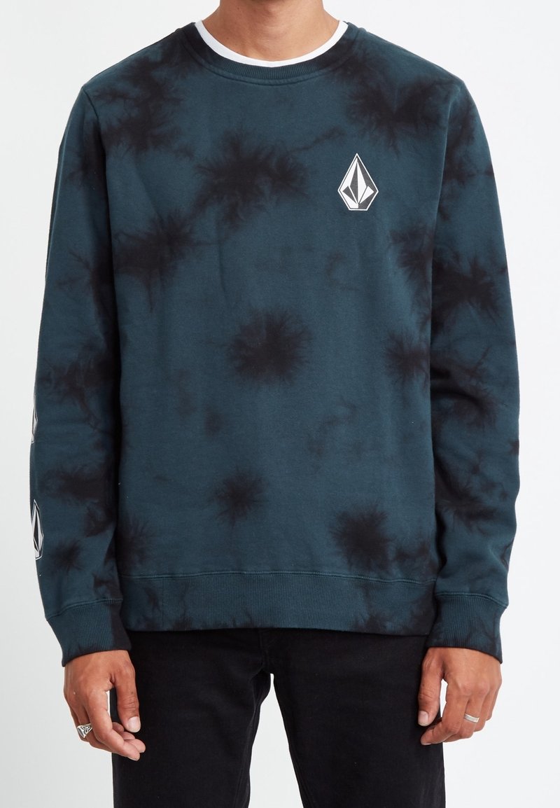 Sudadera de cuello redondo en tie-dye verde-azul con acentos negros, que presenta un parche con logo en el frente y puños y dobladillo acanalados. Textura suave.