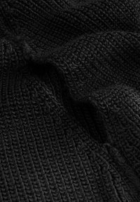 Close-up of black knitted fabric showing detailed ribbed texture and soft folds in the material.