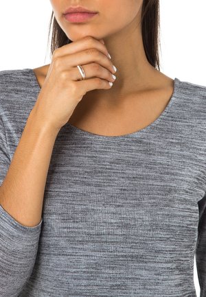 Grå, meleret langærmet top med en bred udskæring. Model med en ring på fingrene, der forsigtigt rører ved sin hage. Glat tekstur.