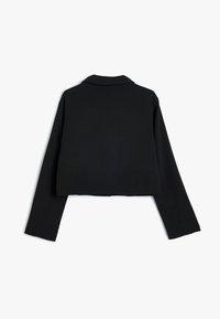 Giacca nera cropped con maniche lunghe, design sartoriale e colletto a scollatura. Realizzata in tessuto testurizzato con una finitura liscia.
