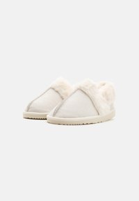 Hvide slippers med en blød, fluffy foring, tekstiloverdel og en struktureret gummisål. Simpelt design med en sømløs æstetik.