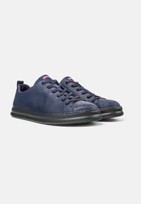 Mörkblå lädersneakers med platta snören, perforerat tådetalj, diskret logotyp och en kontrasterande svart gummisula.