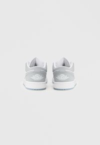 Szare skórzane trampki niskie z białymi środkowymi podeszwami, z logo skrzydła na pięcie i teksturowaną powierzchnią.