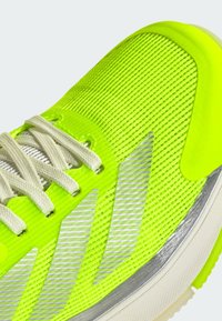 Neon yellow athletic shoe with a mesh upper, silver accents, and white laces. Features textured surface and sleek design with a rounded toe.