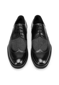 Černé kožené společenské boty s panely z tkaniny s vzorem houndstooth, kulaté špičky a šněrováním, zobrazené z vrchu na bílém pozadí.
