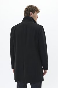 Manteau en laine noir avec un col montant, des manches longues et une coupe droite. Présente des lignes épurées et un design discret sans embellissements.