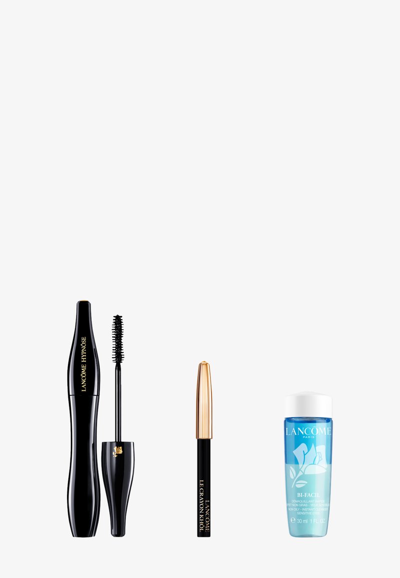 Mascara noir Lancôme avec applicateur, crayon eye-liner noir à embout doré, et petite bouteille bleue de démaquillant pour les yeux.