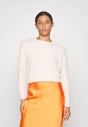 Helles rosa, flauschiges kurz geschnittenes Sweatshirt mit langen Ärmeln, kombiniert mit einem glänzenden orangefarbenen Satinrocks, der einen sanften und lebhaften Kontrast schafft.