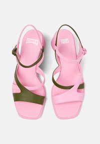 Pink sandals with an olive green strap, featuring a square toe and crisscross design. Made from smooth, lightweight material.