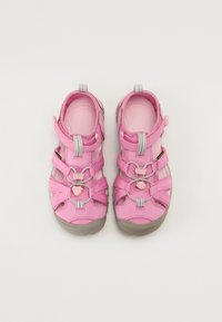 Pink outdoor sandals with gray accents, made of synthetic material. Features adjustable straps and a textured sole for traction.