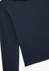 Marineblauwe langemouwen cropped shirt van zacht materiaal. Heeft een ronde halslijn en een gestikte zoom, met een gladde textuur en een minimalistisch ontwerp.
