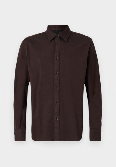 Tamsiai rudas ilgas rankovėmis marškinys, pagamintas iš austos medžiagos. Jame yra mygtukų apykaklė, priekinė plokštelė su juodais mygtukais ir užsegamos rankogaliai.