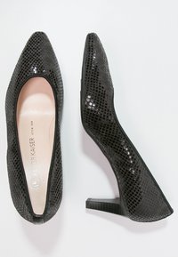 Chaussures à talons hauts noires avec une surface texturée à motif reptilien. Design à bout pointu et talon bloc de taille modérée. Intérieur doublé ; branding minimal visible.