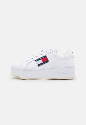 Bílé kožené tenisky s platformou, zdobené červenými a modrými logy na boku a texturovanou gumovou podrážkou.