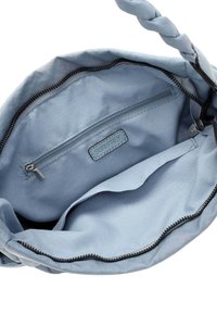 Intérieur d'un sac à main en tissu bleu clair avec une poche zippée et un patch logo. Texture douce avec une poignée tressée et une fermeture zippée.