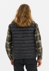 Schwarze Pufferweste mit horizontalem Steppmuster, getragen über einem karierten Flanellhemd in Grün und Beige. Strukturierte Oberfläche, leichtes Erscheinungsbild.