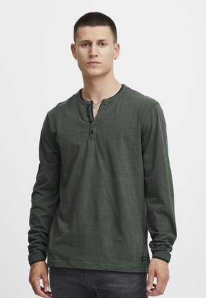 Langärmliges grünes Henley-Shirt aus weichem Material, mit einem Knopfkragen, gerippten Bündchen und minimalistischem Design.