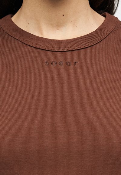 Καφέ ριγωτό βαμβακερό t-shirt με στρογγυλή λαιμόκοψη και ανάγλυφο κείμενο "soeur" στο στήθος. Λεπτή υφή και εφαρμοστό σχέδιο.