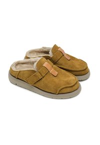 Zapatos en ante marrón, tipo slip-on, con un interior suave, que presentan una correa acolchada y una suela de goma gris. Punta redondeada y diseño minimalista.