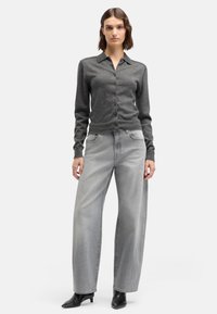 Szary kardigan zapinany na guziki z kołnierzykiem, połączony z szerokimi szarymi jeansami. Strój cechuje subtelna faktura i dopasowane mankiety.